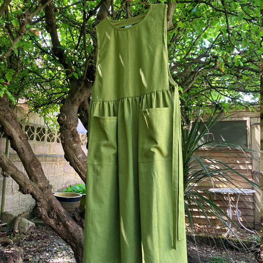 Pea green womens pinafore apron in natural fabric.