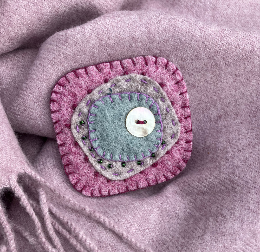 Handmade natural felt brooch. Pink, grey and duckegg blue with mother of pearl button and beads.