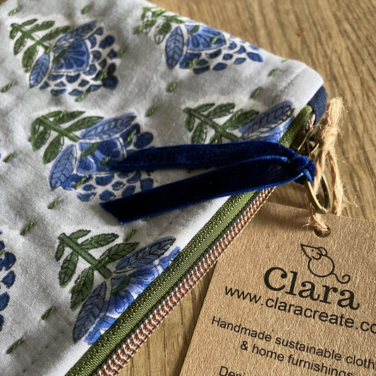 An individual handmade cotton and linen zipper pouch bag, block printed by hand in light blue with darker blue flowers, green  foliage and slow stitch embellishment. Sustainably made for your daily storage, essentials, toiletries, jewellery, stationary or craft items and treasures.