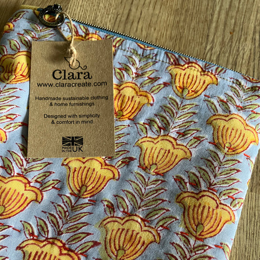 An individual cotton and linen zipper pouch bag, block printed by hand in light blue with gold flowers, green  foliage and slow stitch embellishment. Sustainably made for your daily storage, essentials, toiletries, jewellery, stationary or craft items and treasures.