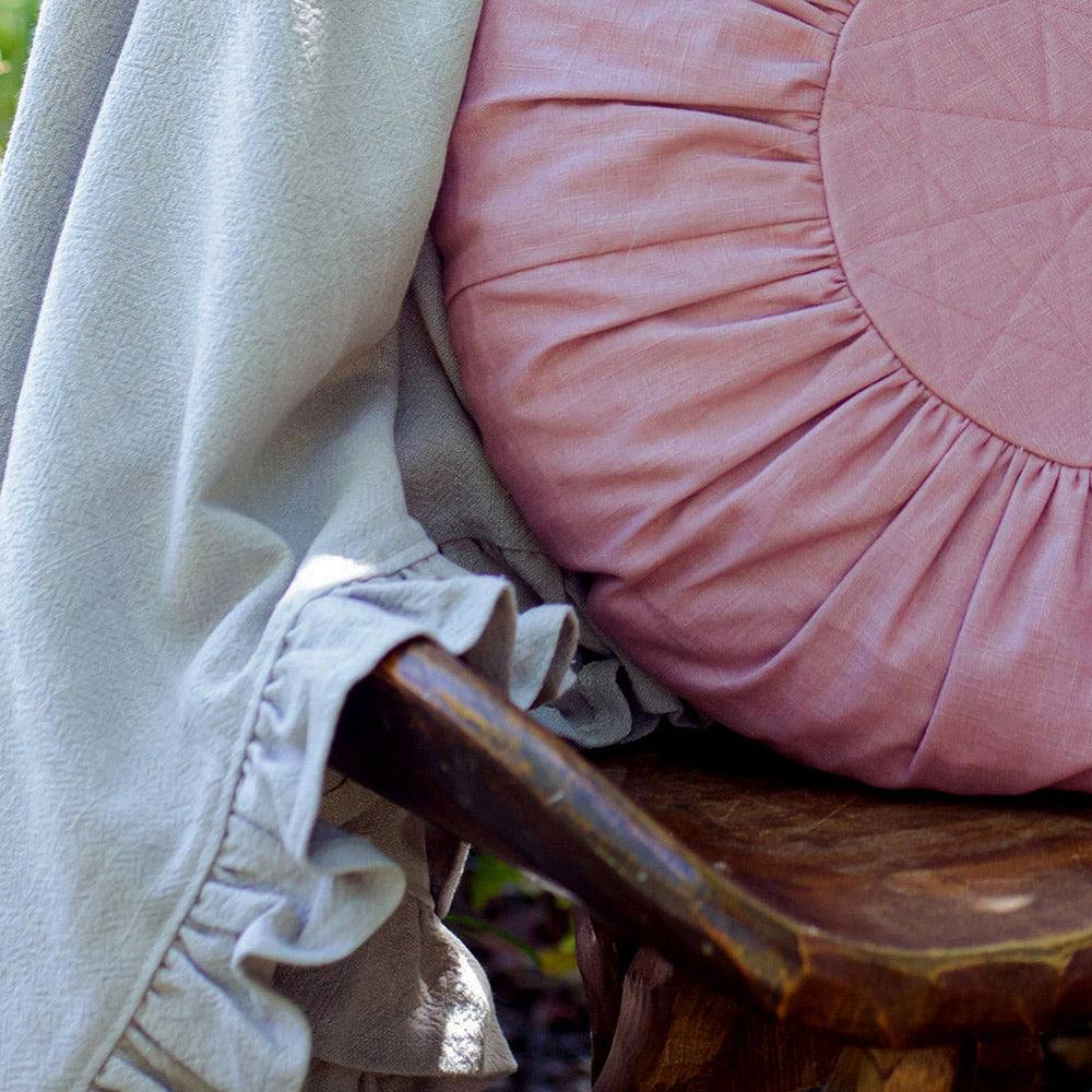 Round Linen Cushion in Heather Pink on a chair